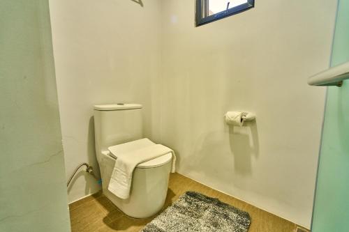 a bathroom with a toilet with a rug and a window at Uno Maya by Araw Residences in Nasugbu