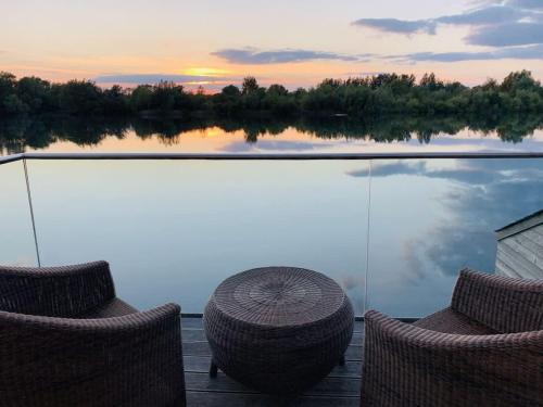 a deck with chairs and an umbrella and a view of a lake at Malachite in South Cerney