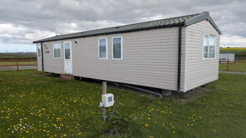 a small house sitting in a field of grass at The Speculation Inn - 3 Bedroom Static Caravan in Pembroke