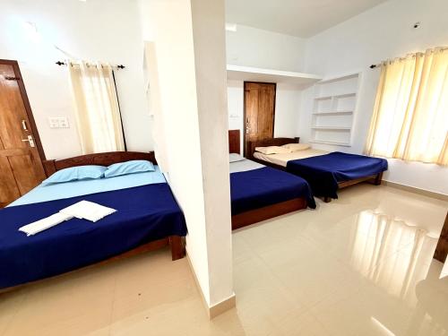two beds in a room with blue sheets at Nariman's riverstone hevan Resort in Kelakam