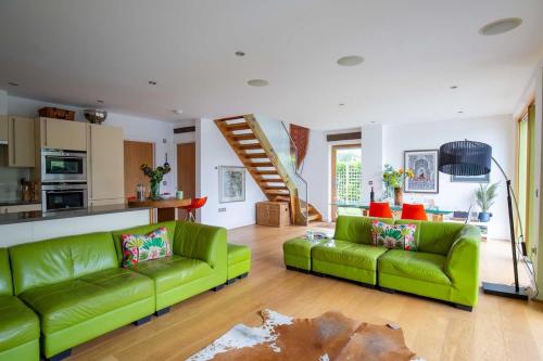 a living room with two green couches and a kitchen at Goose Landing in South Cerney