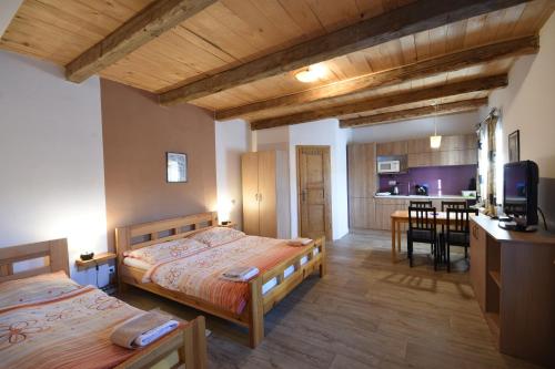 a bedroom with two beds and a kitchen with a table at Pension U Řehoutů in Horní Planá