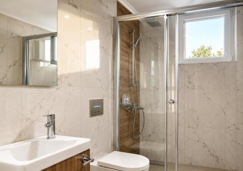 a bathroom with a shower and a toilet and a sink at Nothern Cyprus Four Seasons Life Collection Apartments & Lofts Seafront in Ayios Dhometios
