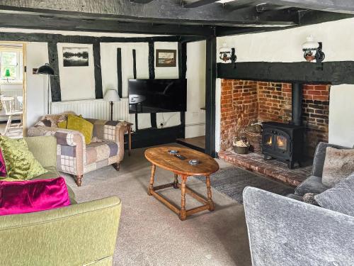 a living room with a brick fireplace and a table at Willow Cottage in Framlingham