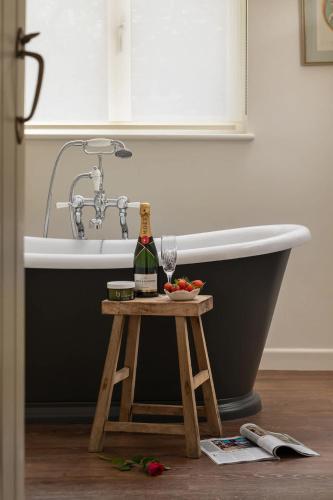 a bottle of wine on a table next to a bath tub at Hill View in Burford