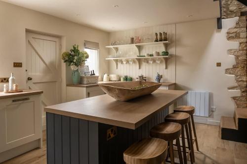 a kitchen with a bowl sink on a counter with stools at Hill View in Burford