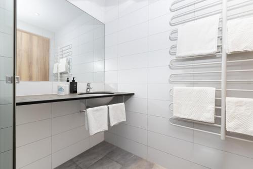 a white bathroom with a sink and white towels at first Apart in Erlangen