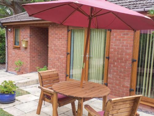 a wooden table with an umbrella on a patio at Little Acorns in Great Malvern