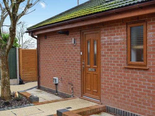 a brick house with a wooden door and a tree at The Squirrels in Great Malvern
