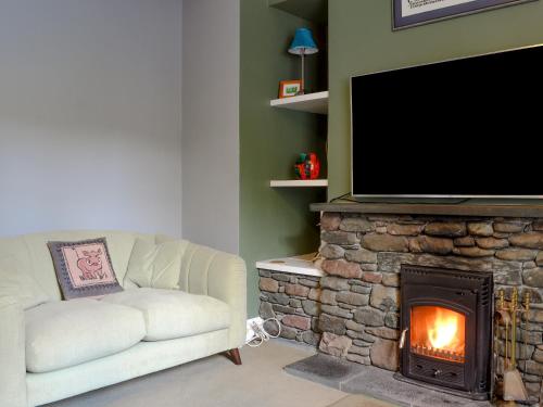 a living room with a couch and a fireplace with a television at Trevene in Buttermere