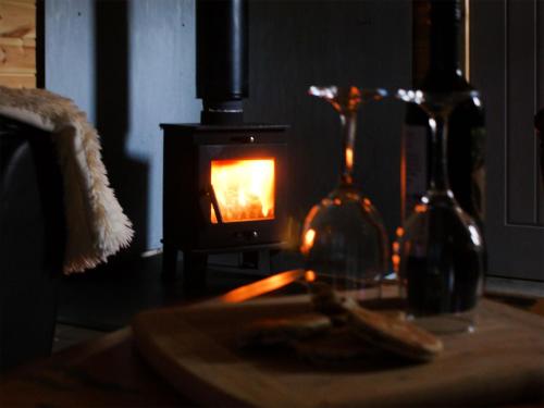 a room with a stove with two wine bottles and a table at Creyr Glas Pod -Uk41796 in Hirnant