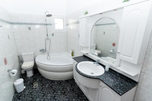 a white bathroom with a toilet and a sink at Kosta Villa Alykes in Lefkimmi