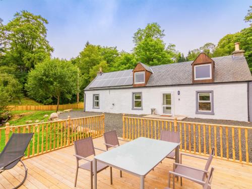 a house with a deck with a table and chairs at Dalnaglar Cottage - Uk30260 in Cray