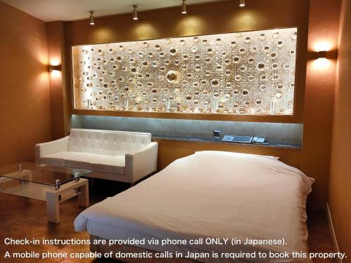 a room with a bed and a couch and a wall at アネックス艶 -大人専用- in Fuefuki