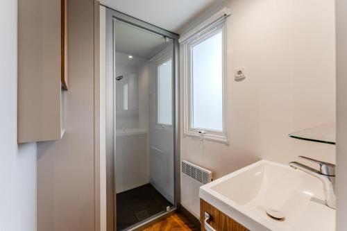 a white bathroom with a shower and a sink at Mobil-home Badji in Gastes