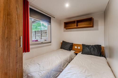 two beds in a small room with a window at Mobil-home Badji in Gastes