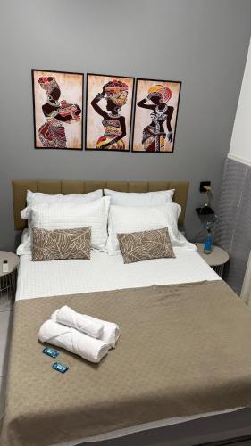a bed with two towels and three pictures on the wall at Apartamento em Lauro de Freitas in Lauro de Freitas