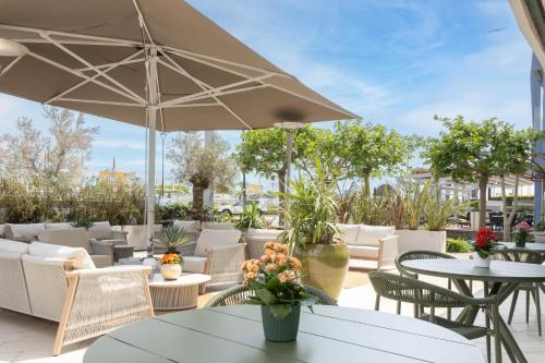 a patio with tables and chairs and an umbrella at Alda Seaview Hotel in Cervia