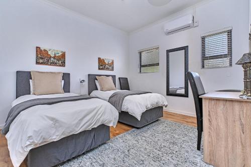 two beds in a room with white walls and a desk at 4 Kiaat Suites in Klerksdorp