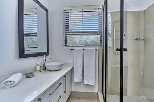 a white bathroom with a shower and a sink at 4 Kiaat Suites in Klerksdorp
