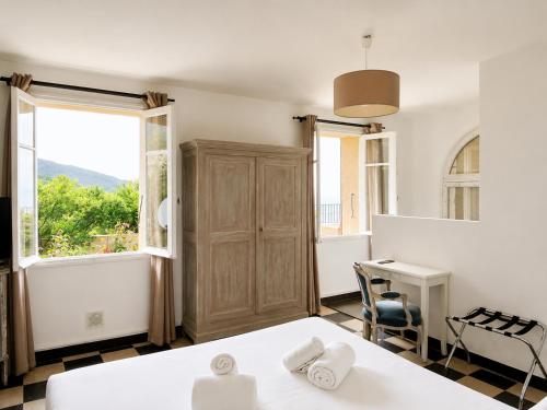 a bedroom with a bed and a desk and a window at Hôtel Villa Les Orangers in Olmeto