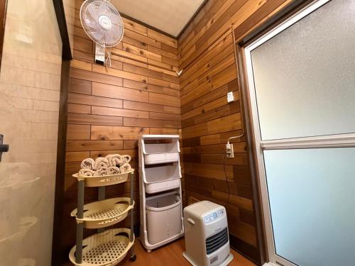 a small bathroom with wooden walls and a refrigerator at 民泊ごとう in Kitakami