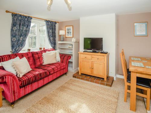 a living room with a red couch and a television at Keepers Cottage - Ukc3950 in Puncknowle