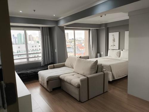 a bedroom with a bed and a couch and window at Airport Gru Flats in Guarulhos
