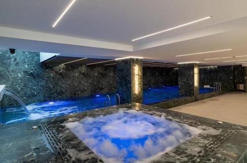 a jacuzzi in a room with blue water at PREMIUM Apartament & Wellness with jacuzzi, sauna , gym , pool in Bucharest