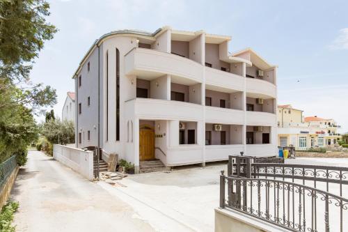 a white building with a fence in front of it at Mala Mara in Kaštela