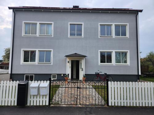 a gray house with a white fence in front of it at Prisvärt semesterboende in Vadstena