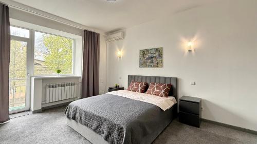a bedroom with a bed and a large window at Calm Central Apartment in Kharkiv