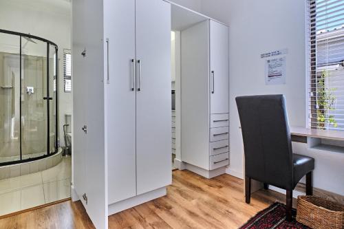 a bathroom with white cabinets and a black chair at 2 Kiaat Suites in Klerksdorp