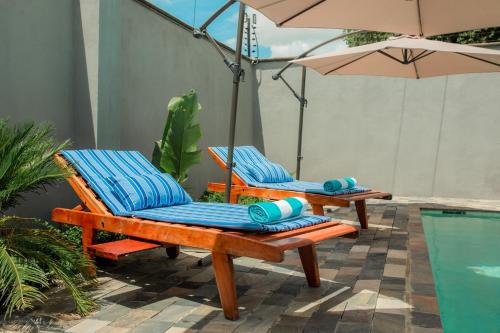 two lounge chairs and an umbrella next to a pool at Chandamali Bed & Breakfast in Kitwe