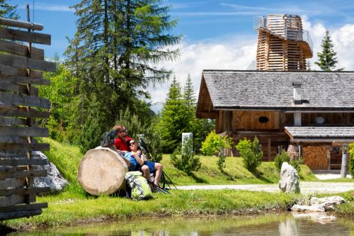 a man and a woman sitting on a log next to a river at Caravan Park Sexten in Sesto