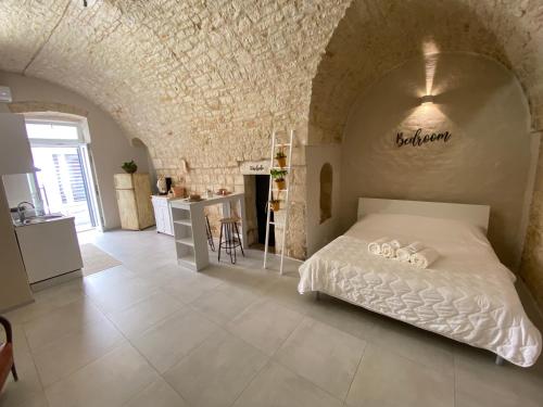 ein Schlafzimmer mit einem weißen Bett in einer Steinwand in der Unterkunft Amber's House in Casamassima