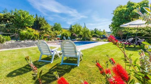two chairs sitting in the grass near a swimming pool at Cortijo Noguera La Taha - Pitres by Ruralidays in Granada