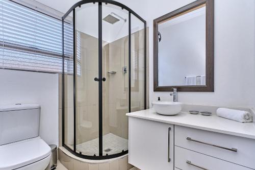 a bathroom with a shower and a toilet and a sink at 3 Kiaat Suites in Klerksdorp