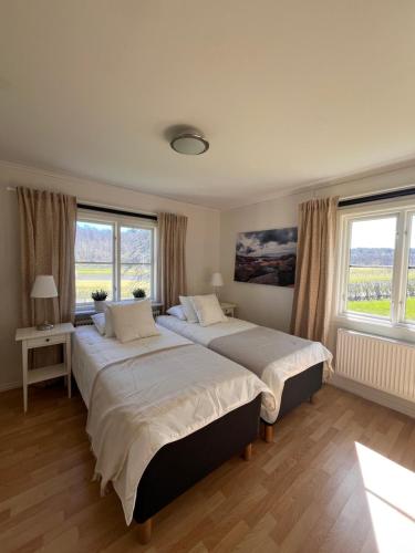 two beds in a bedroom with two windows at Holma Stångenäs Golf in Brastad