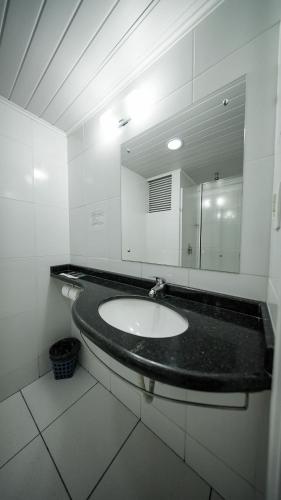 a bathroom with a sink and a mirror at LH Plaza Hotel in Chapecó