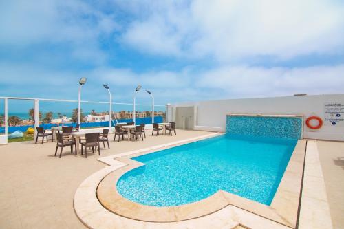 a pool on the roof of a building with tables and chairs at Pallax hotel in Zarzis