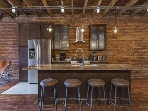 a kitchen with a counter with stools and a refrigerator at The Library-Downtown Nashville Luxury Penthouse Printers Alley Steps to Broadway in Nashville