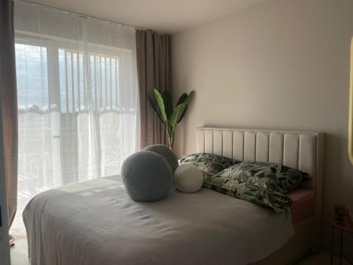 a teddy bear sitting on a bed with a window at Sunday Apartamenty SPA Miraż in Ustronie Morskie