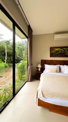 a bedroom with a bed and a large window at 3BR Tala Villa Ubud in Ubud