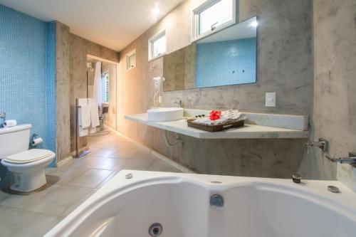 a bathroom with a tub and a toilet and a sink at Armação dos Búzios Pousada Design in Búzios