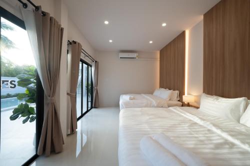a bedroom with two beds and a large window at Sea Vibes Pool Villa in Ban Bo So
