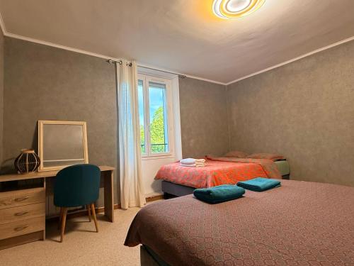 a bedroom with two beds and a desk and a window at Au bord de l eau in Villabé