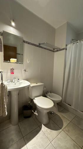a white bathroom with a toilet and a sink at Hotel coventry in Santiago del Estero