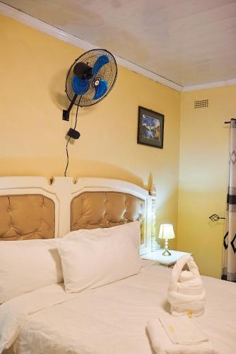 a bedroom with a bed with a fan on the wall at Niyonest Guesthouse in Harare