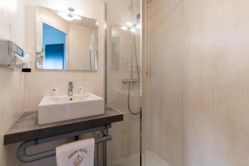 a bathroom with a sink and a shower with a mirror at Abor Hôtel, Mont de Marsan in Saint-Pierre-du-Mont